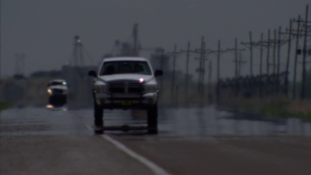 车辆驶过一条被雨打湿的道路，经过一个输电场。视频素材