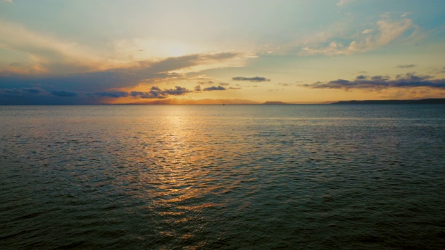 在一个愉快的夏天晚上的海景:美丽的日落，彩色的云，一个纯海与游艇，在水面上闪烁的太阳。海洋，海洋，自然视频旅游，度假和冥想的地点视频素材