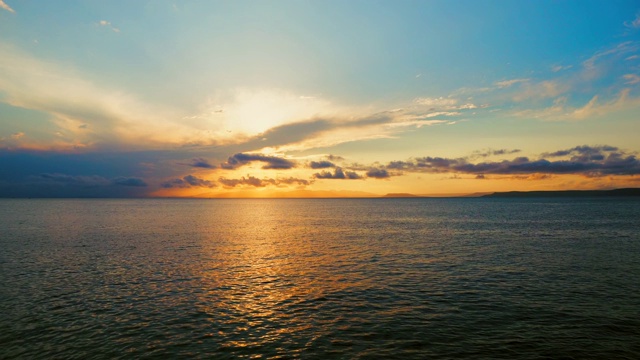 在一个愉快的夏天晚上的海景:美丽的日落，彩色的云，一个纯海与游艇，在水面上闪烁的太阳。海洋，海洋，自然视频旅游，度假和冥想的地点视频素材