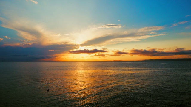 在一个愉快的夏天晚上的海景:美丽的日落，彩色的云，一个纯海与游艇，在水面上闪烁的太阳。海洋，海洋，自然视频旅游，度假和冥想的地点视频素材