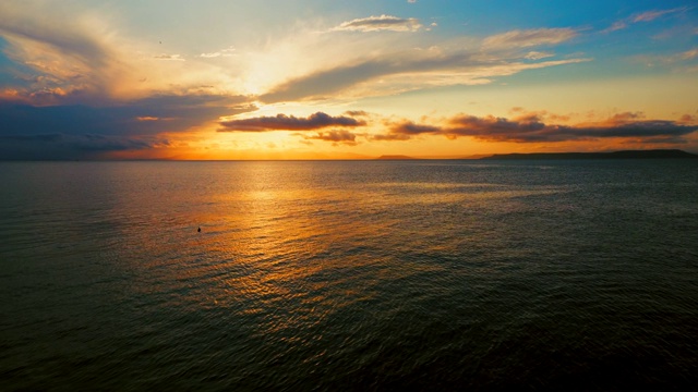 在一个愉快的夏天晚上的海景:美丽的日落，彩色的云，一个纯海与游艇，在水面上闪烁的太阳。海洋，海洋，自然视频旅游，度假和冥想的地点视频素材