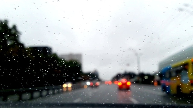 在雨中开车沿着城市街道，水滴落在挡风玻璃上，时间流逝视频素材