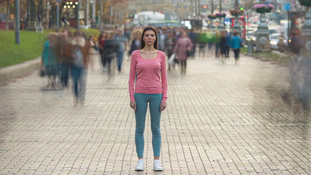 那个女孩背对着人流站在人行道上。时间流逝视频素材