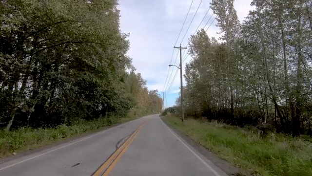 汽车沿着有树和灌木丛的郊区公路行驶，靠近河边和桥视频素材