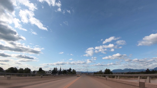 从一辆行驶在高速公路上的汽车挡风玻璃和一座横跨河流的桥上的视角视频素材