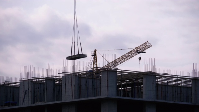 建筑工地上的塔式起重机在高层建筑中吊装重物视频素材