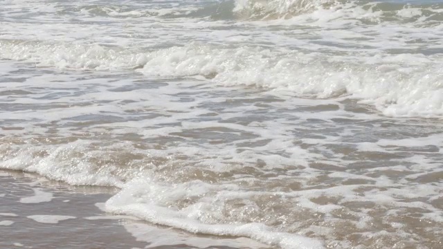 泡沫的海浪蔓延在阳光明媚的海滩夏日假期背景4K视频素材