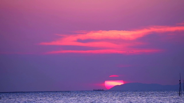 夕阳和紫色的云在天空上，海面上小波浪移动视频素材