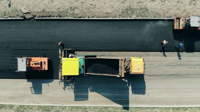 工人们正在用沥青筑路。公路施工现场的沥青摊铺机。视频素材