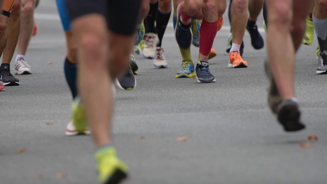 马拉松赛跑的慢动作镜头。人们在城市的道路上行走视频素材