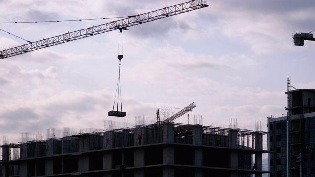 建筑工地上的塔式起重机在高层建筑中吊装重物视频素材