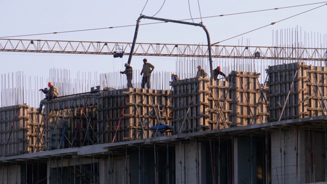 建筑工地上的建筑工人们。建筑工地上的起重机吊起重物。建筑施工视频素材