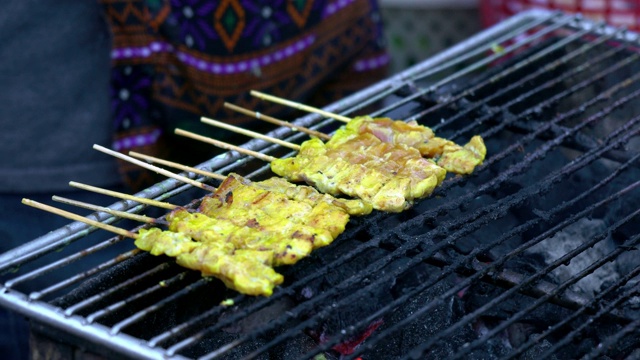 在热炭烤架上熏烤猪肉，泰国街头小吃。视频素材