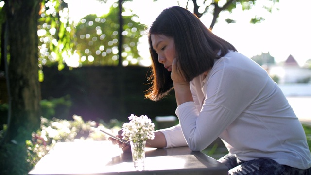 日落时分，一名女子在户外公园使用手机视频素材