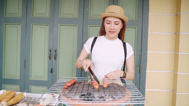 旅行者女孩很喜欢在炉子上手动烤食物。亚洲妇女欣赏曼谷的地标性建筑，曼谷的佛寺视频素材