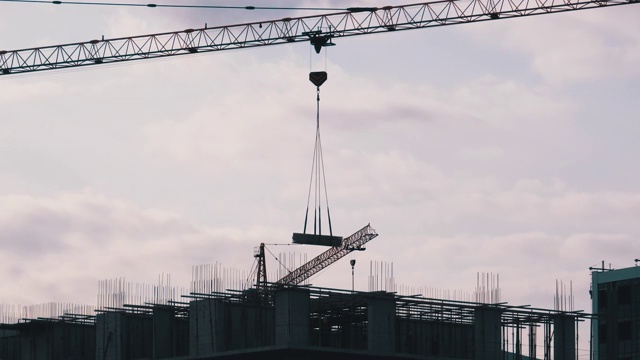 建筑工地上的塔式起重机在高层建筑中吊装重物视频素材