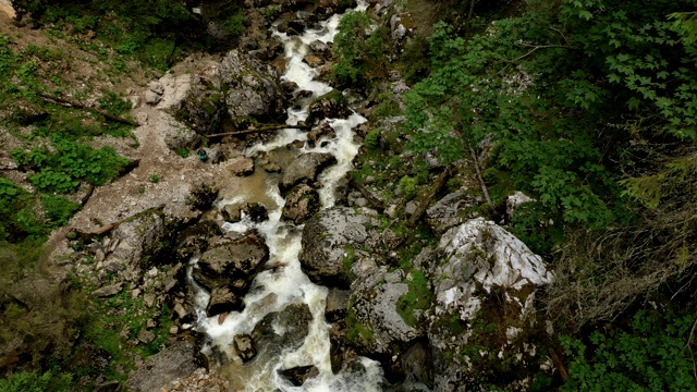 罗马尼亚阿普塞尼山脉Padis高原，一条山间小溪流经松林，进入Cetatile Ponorului喀斯特洞穴的入口视频素材