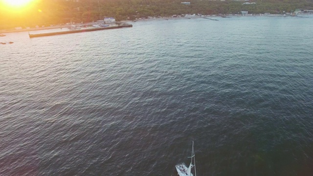 阳光明媚的傍晚，游艇从绿色海岸远航的鸟瞰图视频素材