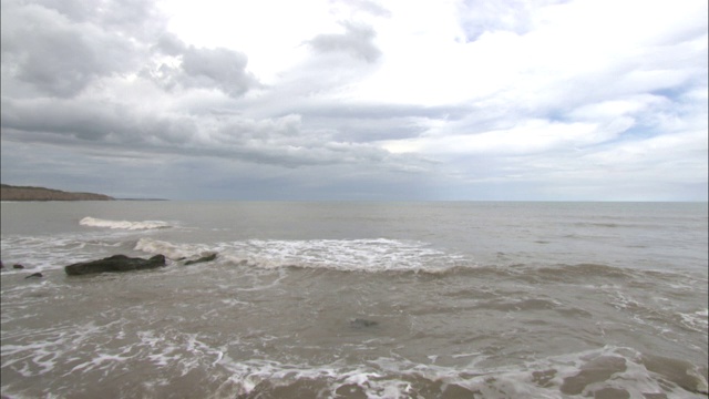 海浪拍打着悬崖边的海滩。视频素材