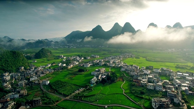 鸟瞰喀斯特山峰森林(万峰林)中的村庄和稻田，贵州，中国。视频素材