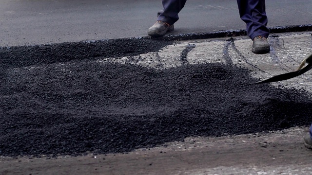 糟糕的道路。压路机和工人在铺沥青和修复城市街道。视频素材