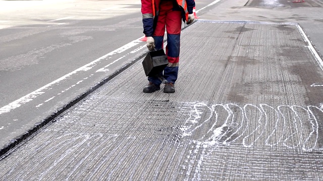 道路维修。工作细节上，工人们将树脂浇筑路面以覆盖沥青。视频素材