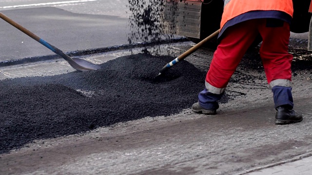 糟糕的道路。压路机和工人在铺沥青和修复城市街道。视频素材