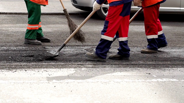 糟糕的道路。压路机和工人在铺沥青和修复城市街道。视频素材