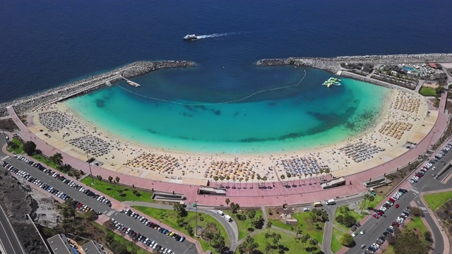 飞过阳光明媚的阿马多雷斯海滩(Playa de Amadores)和蓝绿色的大海，大加那利群岛，加那利群岛，西班牙视频素材