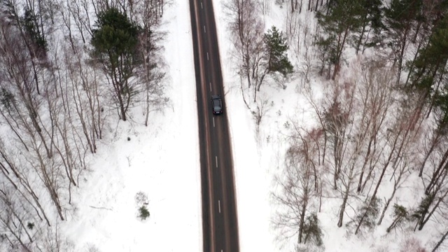 汽车通过冬季森林道路的鸟瞰图。风景优美的冬季景观。前跟踪拍摄视频素材