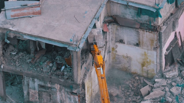 在建筑工地用斗式挖掘机拆除旧房子视频素材