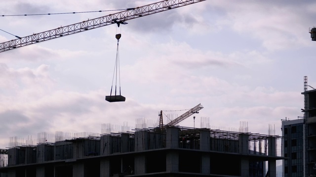 建筑工地上的塔式起重机在高层建筑中吊装重物视频素材