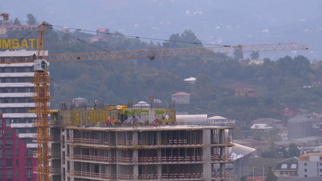 建筑工地的工人。建筑工地上的起重机吊起重物视频素材