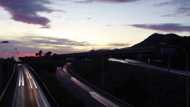 在美丽的夕阳下，长时间曝光的灯光在高速公路上行驶。视频素材