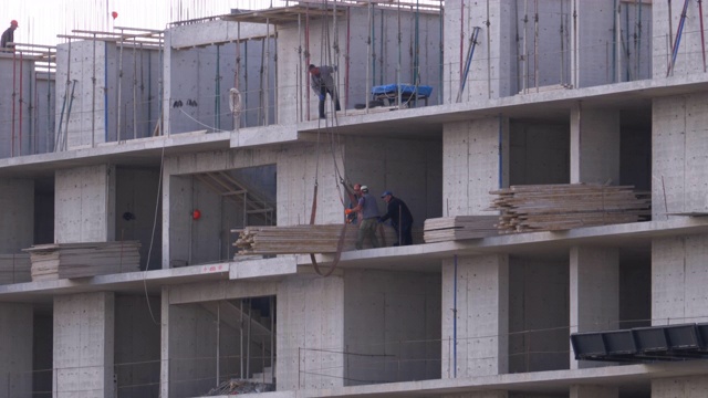 建筑工地的工人。建筑工地上的起重机在吊起货物视频素材