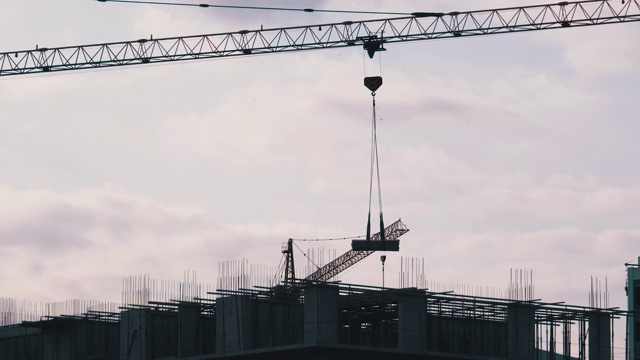 建筑工地上的塔式起重机在高层建筑中吊装重物视频素材