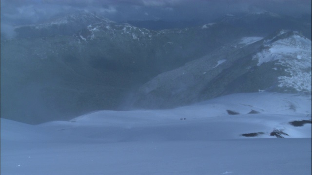 风一吹，徒步旅行者就穿过山上的一大片积雪。视频素材