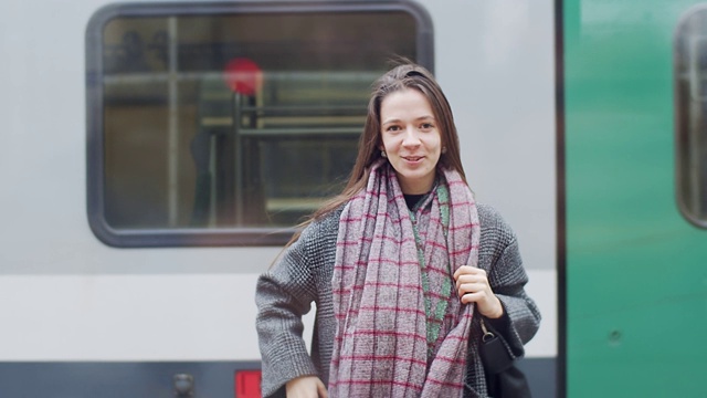 在离开火车站前，年轻女子挥手告别的正面肖像视频素材