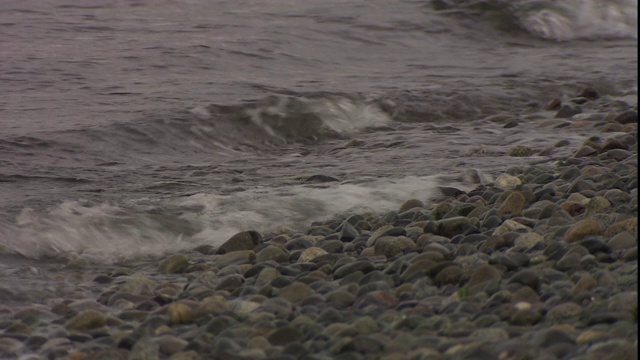 波浪冲刷着布满卵石的海岸。视频素材