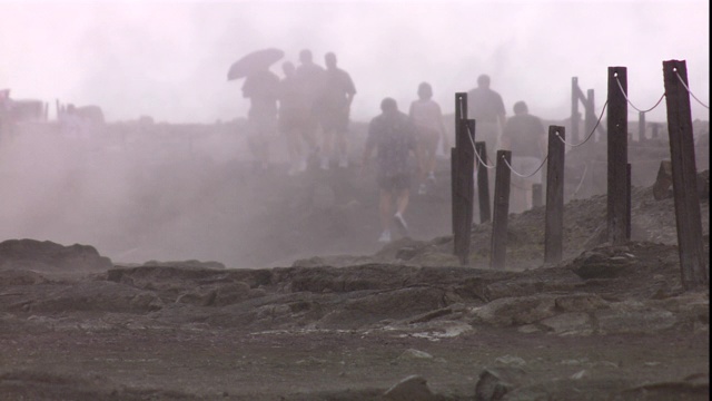 游客们在基拉韦厄火山口周围漫步，蒸汽从地热喷口翻腾而出。视频素材