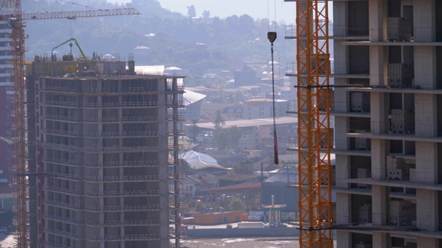 建筑工地上的塔式起重机在高层建筑中吊装重物视频素材