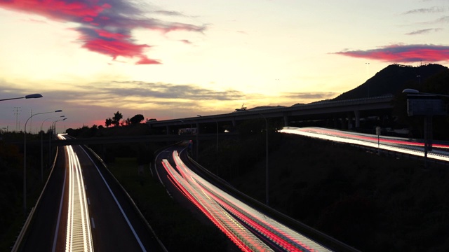 在美丽的夕阳下，长时间曝光的灯光在高速公路上行驶。视频素材