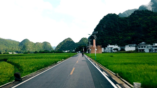 汽车行驶在稻田和村庄的路上，贵州，中国。视频素材