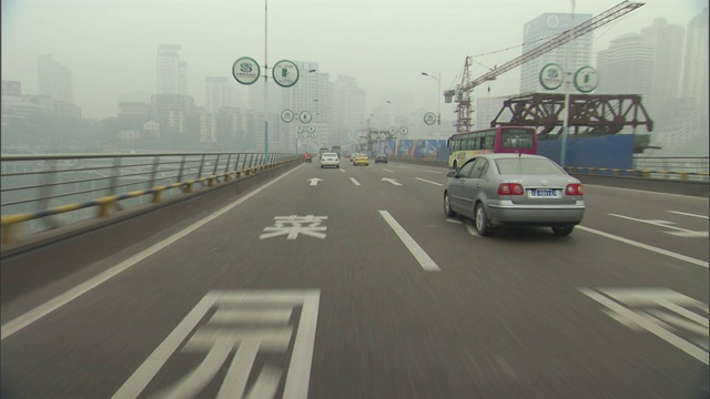 在一个烟雾弥漫的城市里，车辆在一条多车道的道路上行驶。视频素材