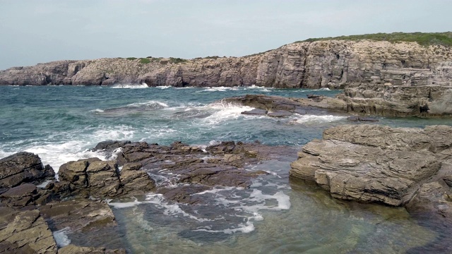 低角度拍摄的岩石湾与翡翠海水撞击岩石视频素材