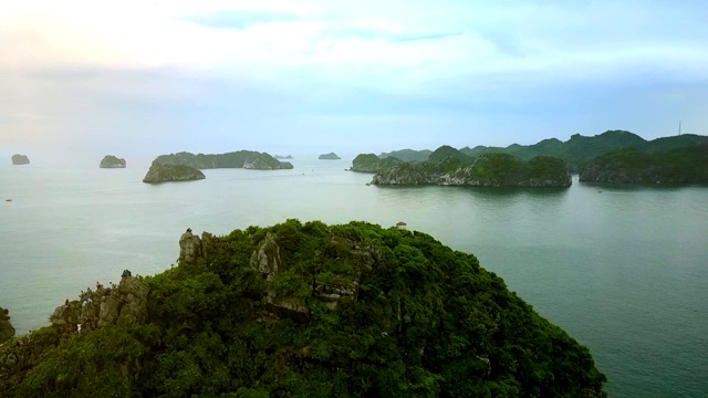 无人机沿着绿岩岛和显示海洋湾飞行视频素材