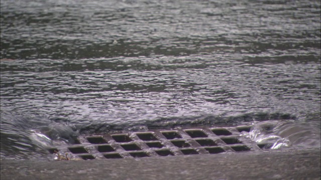 雨水沿着人行道流入街道上的金属格栅。视频素材