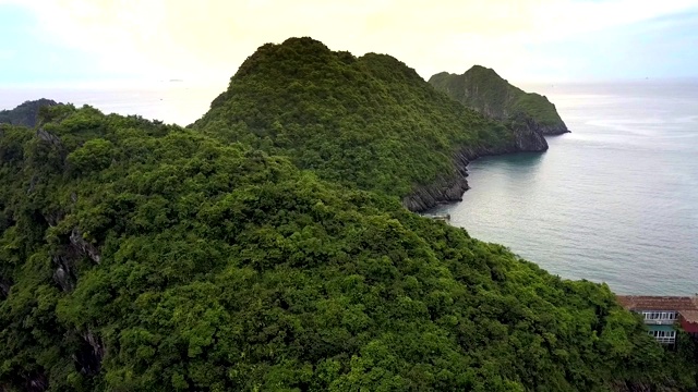 无人机飞在绿岩岛顶对着大洋湾视频素材