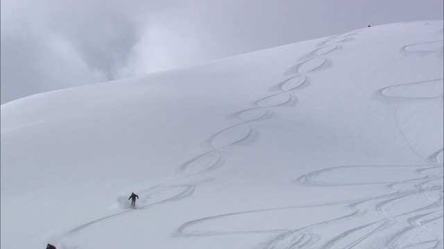 滑雪者在多雪的山坡上滑行。视频素材