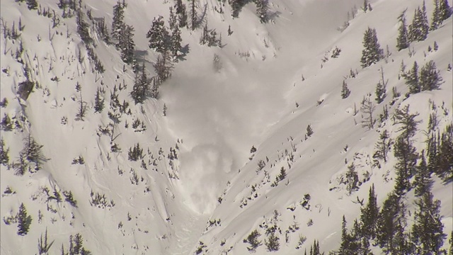 爆炸在白雪皑皑的山坡上造成雪崩。视频素材